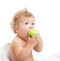 Little curly-headed child eats a green apple and looking up Royalty Free Stock Photo