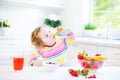 Little curly toddler girl having breakfast drinking juice Royalty Free Stock Photo