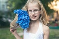 Little cute adorable blond caucasian little female child girl portrait hold beautiful fresh blue hydrangea bouquet Royalty Free Stock Photo