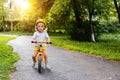 Little cute adorable caucasian toddler girl having fun riding exercise balance run bike push scooter in park forest. Royalty Free Stock Photo