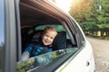 Little cute adorable happy caucasian toddler boy sitting in child safety seat car open window enjoy having fun making Royalty Free Stock Photo