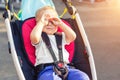 Little cute adorable toddler kid boy rubbing eyes with hands sitting in stroller on bright summer day outdoors. Tired Royalty Free Stock Photo