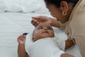 Little cute African American newborn baby lying on bed and looking smiling at young mother who is touching infant`s head Royalty Free Stock Photo