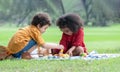 Little cute African children boy and girl sitting and have fun playing fruits and wooden blocks while picnic at park together. Royalty Free Stock Photo