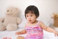 Little cute asian baby girl sitting on bed playing Royalty Free Stock Photo