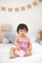 Little cute asian baby girl sitting on bed playing Royalty Free Stock Photo
