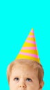 Little cute baby with blue eyes wearing birthday cap against blue background. Contemporary art collage. Concept of Royalty Free Stock Photo