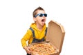 Little cute baby boy in a yellow sweater and denim overalls and blue sunglasses shouts loudly and holds an open box with pizza iso Royalty Free Stock Photo