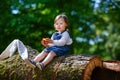 Little cute baby girl eating fruit in forest Royalty Free Stock Photo