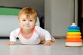 Little cute baby girl learning to crawl. Healthy child crawling in kids room. Smiling happy healthy toddler girl. Cute