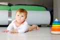 Little cute baby girl learning to crawl. Healthy child crawling in kids room. Smiling happy healthy toddler girl. Cute