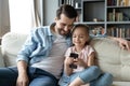 Happy young dad watching small daughter playing game on smartphone. Royalty Free Stock Photo