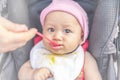 Little cute baby girl sits on a chair and eating with spoon. Mother feeding baby holding out her hand with a spoon of food made Royalty Free Stock Photo