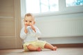 Little cute baby girl sitting in room on floor drinking water from bottle and smiling. Happy infant. Family people indoor Interior Royalty Free Stock Photo