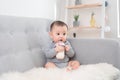 Little cute baby girl sitting in room on sofa drinking milk from bottle and smiling. Happy infant. Family people indoor Interior Royalty Free Stock Photo