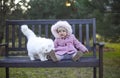 Little cute baby girl wearing autumn outfit and white cat sitting on the bench Royalty Free Stock Photo