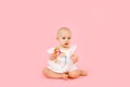 Little cute baby girl 1 years old wearing white summer dress isolated on pastel pink wall background, children studio portrait. Royalty Free Stock Photo