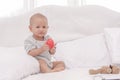 Little cute baby one year girl sitting and playing alone on white bed Royalty Free Stock Photo