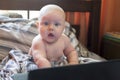Little cute baby sitting in front of laptop in bed Royalty Free Stock Photo