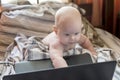 Little cute baby sitting in front of laptop in bed Royalty Free Stock Photo