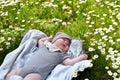 Little cute baby sleeping on the grass lawn with daisies