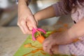 Little cute baby toddler girl in the kitchen peeling carrots with carrot peeler on chopping board. Child help at home