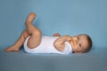 little cute baby in a white bodysuit baby lies isolated on a blue background Royalty Free Stock Photo