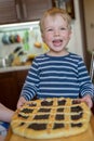 Little cute blond boy with happy smile enjoys baked berry pie with wild berry jam. Concept of happy childhood