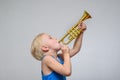 Little cute blond boy playing toy trumpet on light background Royalty Free Stock Photo