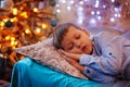 Little cute blond boy sleeping under Christmas tree and dreaming Royalty Free Stock Photo