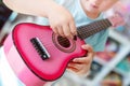 Little cute blond girl having fun learning to play small ukulele guitar at home.Toddler girl playing toy musical Royalty Free Stock Photo