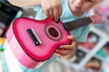 Little cute blond girl having fun learning to play small ukulele guitar at home.Toddler girl trying to play toy musical Royalty Free Stock Photo