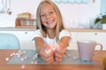 Little cute blond girl in the kitchen having her breakfast having fun with marshmallow and smiling. This is so tasty Royalty Free Stock Photo