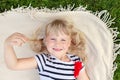 Little cute blond girl lying on blanket over green grass lawn and smiling. Adorable child having fun outdoors. Happy family, paren Royalty Free Stock Photo