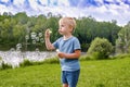 Little cute blond kid boy having fun play blowing soap bubbles at park near lake on bright warm summer spring day.happy healthy Royalty Free Stock Photo