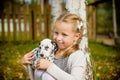 Little cute blonde girl playing with her Dalmatian puppy outdoo, on sunny warm autumn day.care of Pets concept. Child Royalty Free Stock Photo