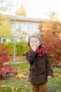 Little cute boy in an autumn coat and cap plays in an autumn park with yellow leaves