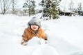 Little cute boy in black hat,orange jacket is lying,playing in snow. Kid walking in beautiful frozen forest,park among Royalty Free Stock Photo