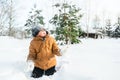 Little cute boy in black hat,orange jacket is lying,playing in snow. Kid walking in beautiful frozen forest,park among Royalty Free Stock Photo