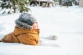 Little cute boy in black hat,orange jacket is lying,playing in snow. Kid walking in beautiful frozen forest,park among Royalty Free Stock Photo