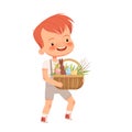 Little cute boy carries a basket with a chocolate hare, colored eggs and osier branches for the Easter holiday. Spring