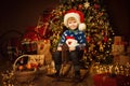 Little Cute Boy in Christmas Decorated Room Interior. Child on vintage wooden Toy Horse. Christmas tree with rustic ornament Royalty Free Stock Photo