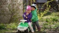 Little cute boy and girl posing on a green toy car in a park early spring Royalty Free Stock Photo