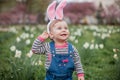 Little cute boy and girl are sitting on the grass near the daffodils. Children in costumes Easter bunnies Royalty Free Stock Photo