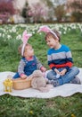 Little cute boy and girl are sitting on the grass near the daffodils. Children in costumes Easter bunnies Royalty Free Stock Photo