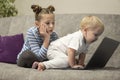 Little cute boy and girl using laptop together, looking at screen, watching cartoons or playing online, sister and brother, Royalty Free Stock Photo