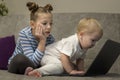 Little cute boy and girl using laptop together, looking at screen, watching cartoons or playing online, sister and Royalty Free Stock Photo