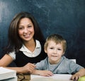 Little cute boy in glasses with young real teacher, classroom studying at blackboard school kido Royalty Free Stock Photo