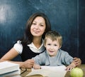 Little cute boy in glasses with young real teacher, classroom studying at blackboard school kido Royalty Free Stock Photo