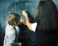 Little cute boy in glasses with young real teacher, classroom studying at blackboard school kido Royalty Free Stock Photo